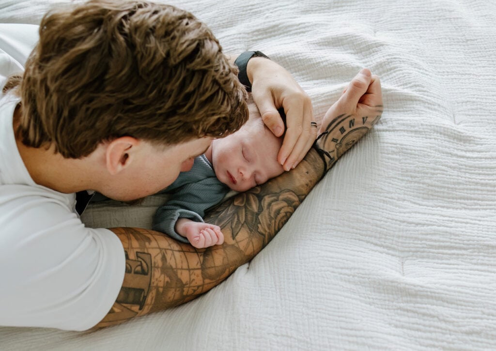 Austin Newborn Photographer, Father laying on bed with newborn baby