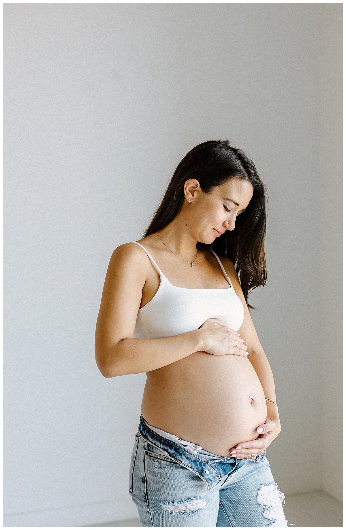 Mother smiles and holds pregnant belly for Studio Maternity Photos