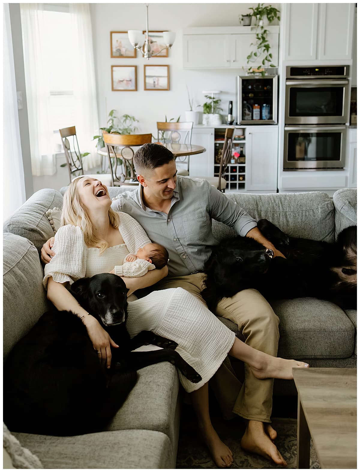 Parents smile and laugh with their baby and digs for In-Home Newborn Storytelling Session