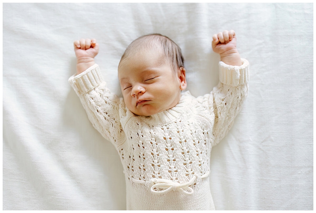 Baby holds hands above her head during her In-Home Newborn Storytelling Session