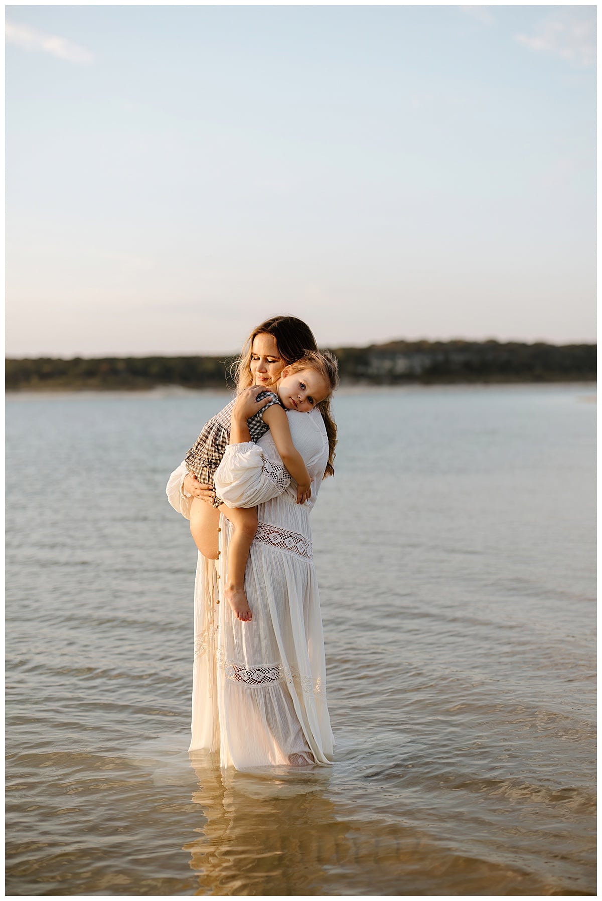 Little girl rests on moms shoulder for Sandy Beach Maternity Session