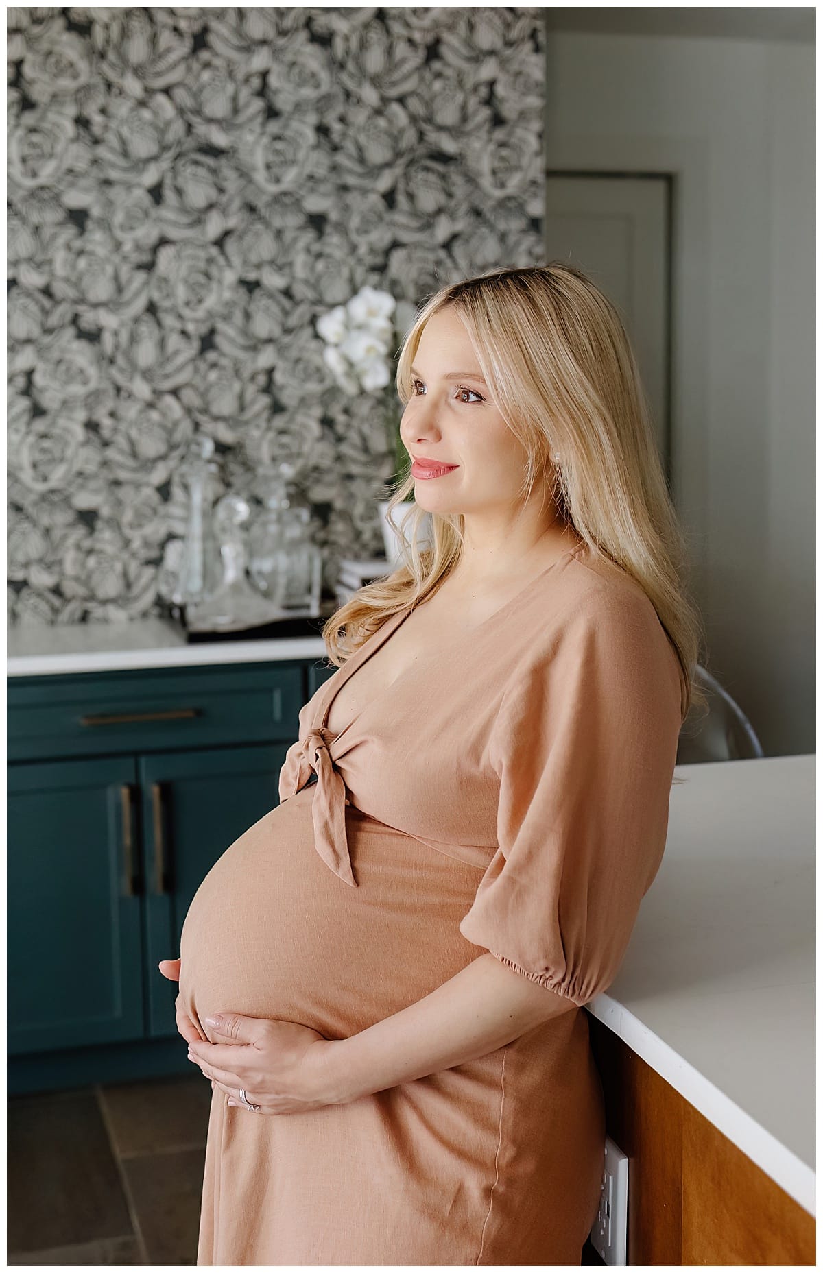 Mom holds pregnant belly for in home maternity session