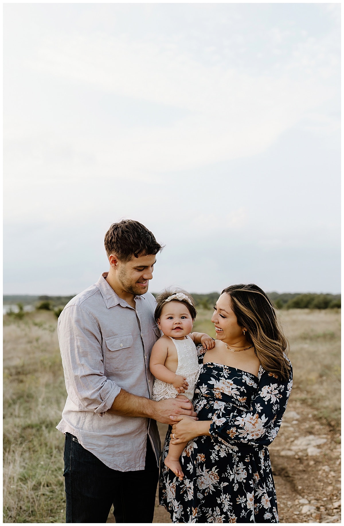 Mom and dad smile at their little baby during First Birthday Family Photos 