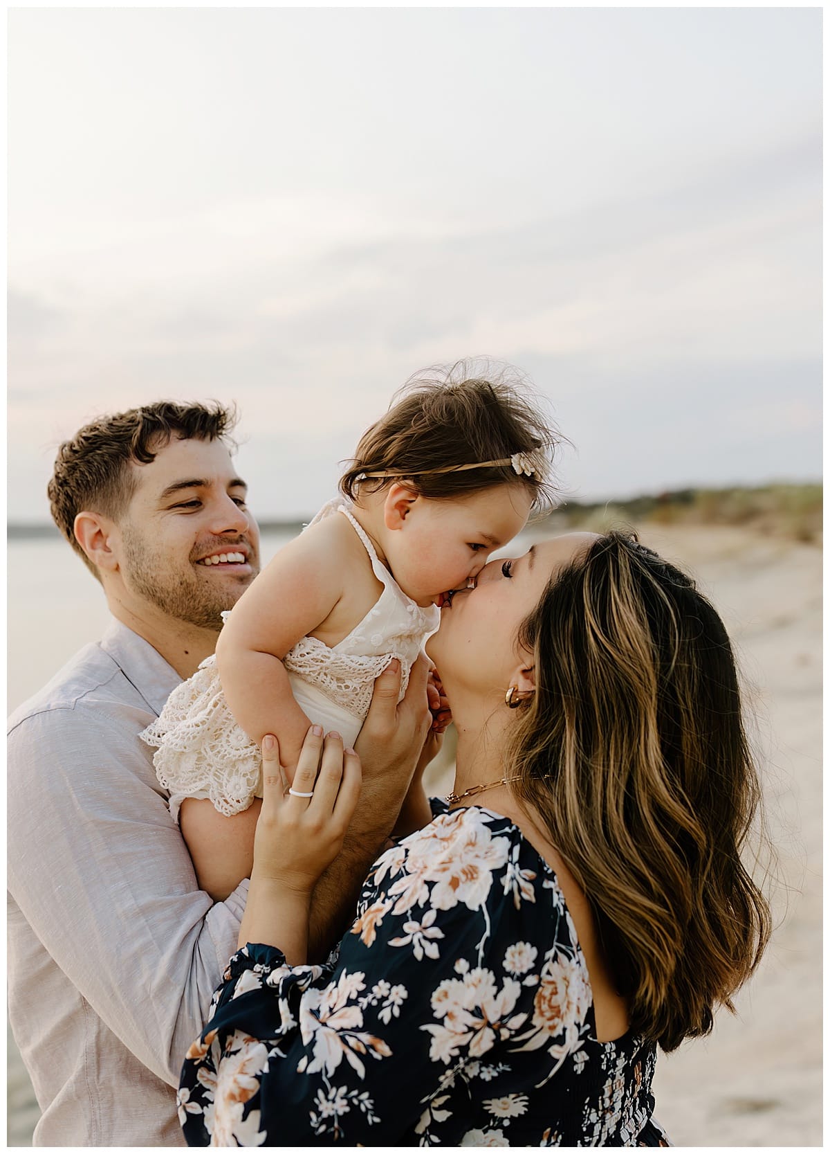 Parents share a kiss with baby for Our Adventuring Souls Photography