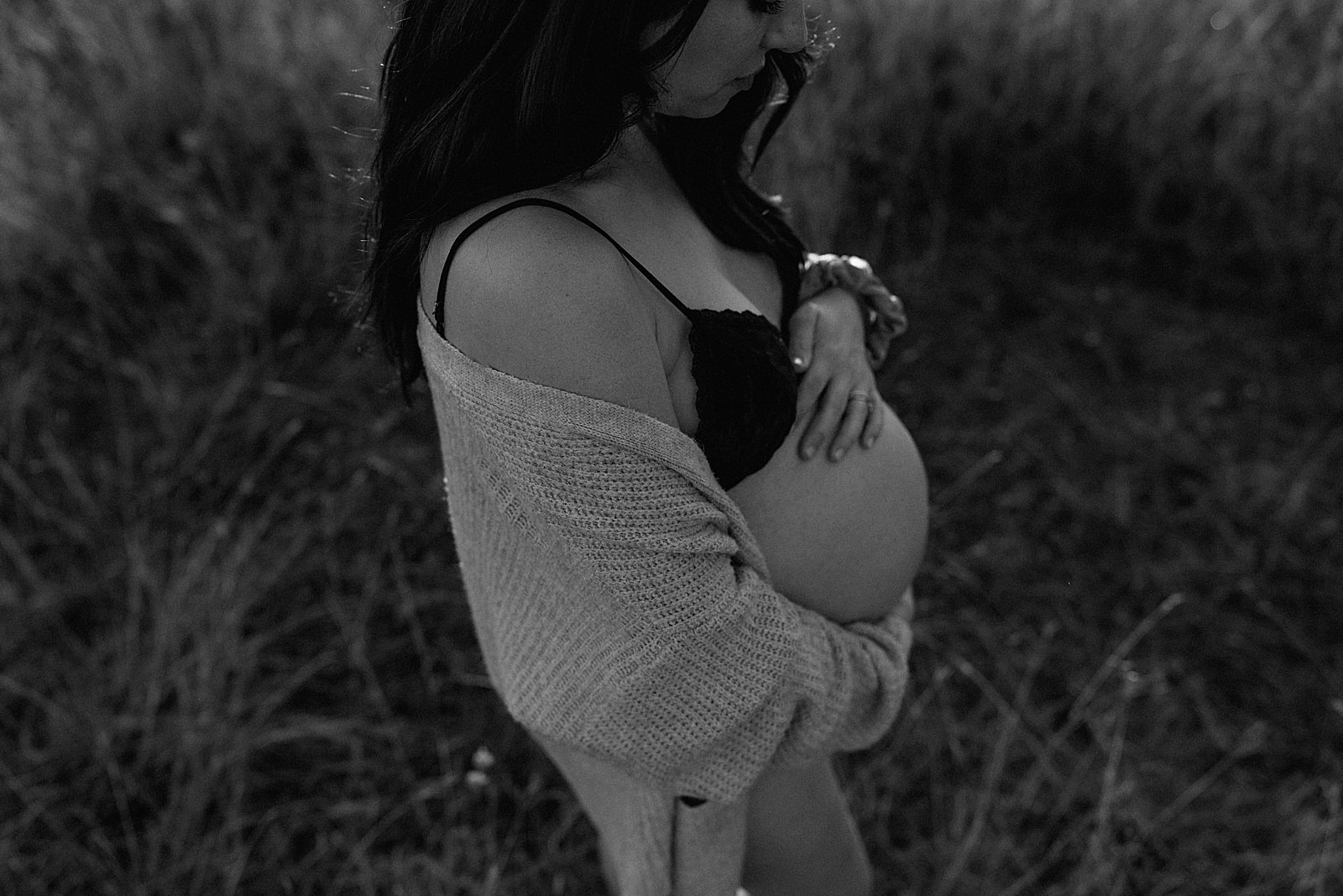 Mom holds pregnant belly during Outdoor Lifestyle Maternity Session