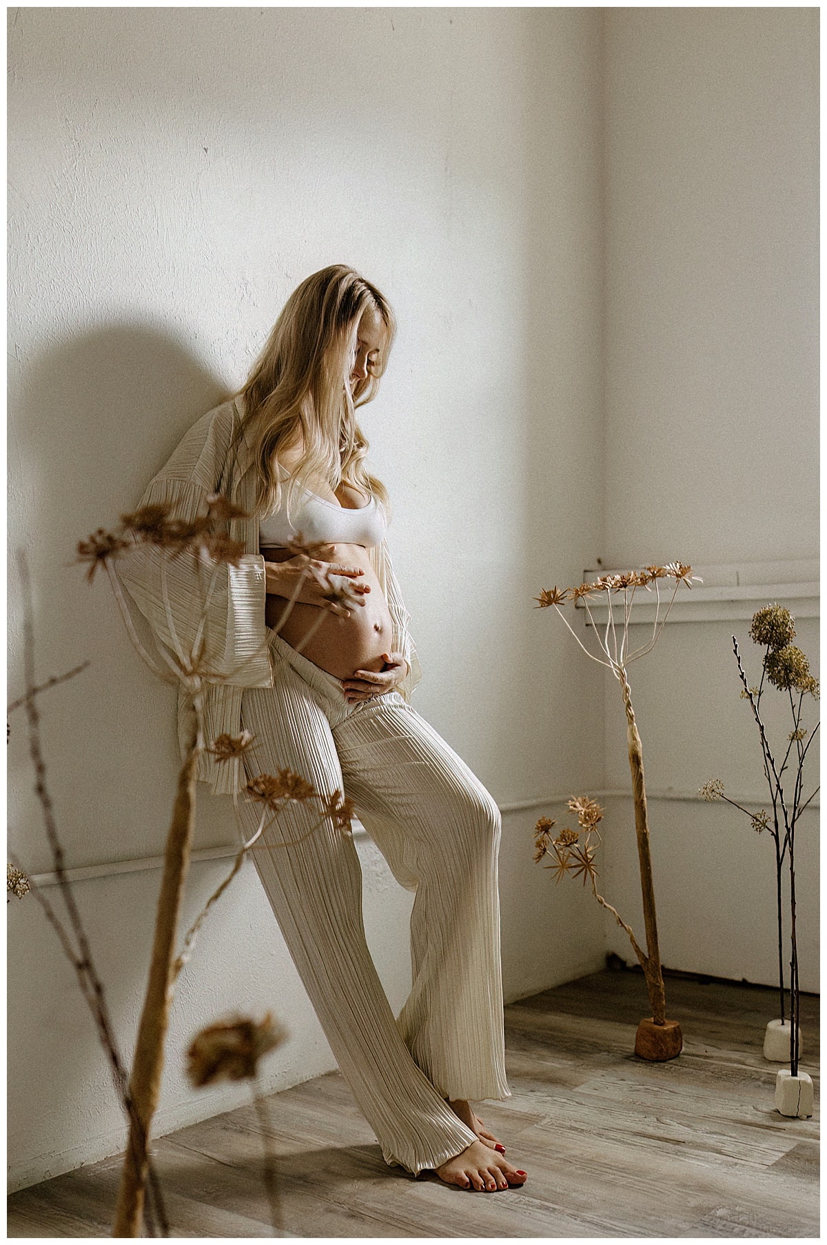 Adult embraces her pregnant belly during her studio maternity session