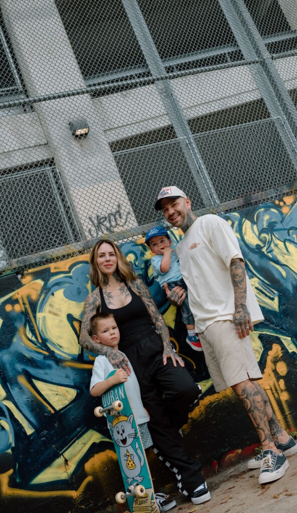 Austin family photographer captures parents and two young children posing together in front of colorful graffiti.