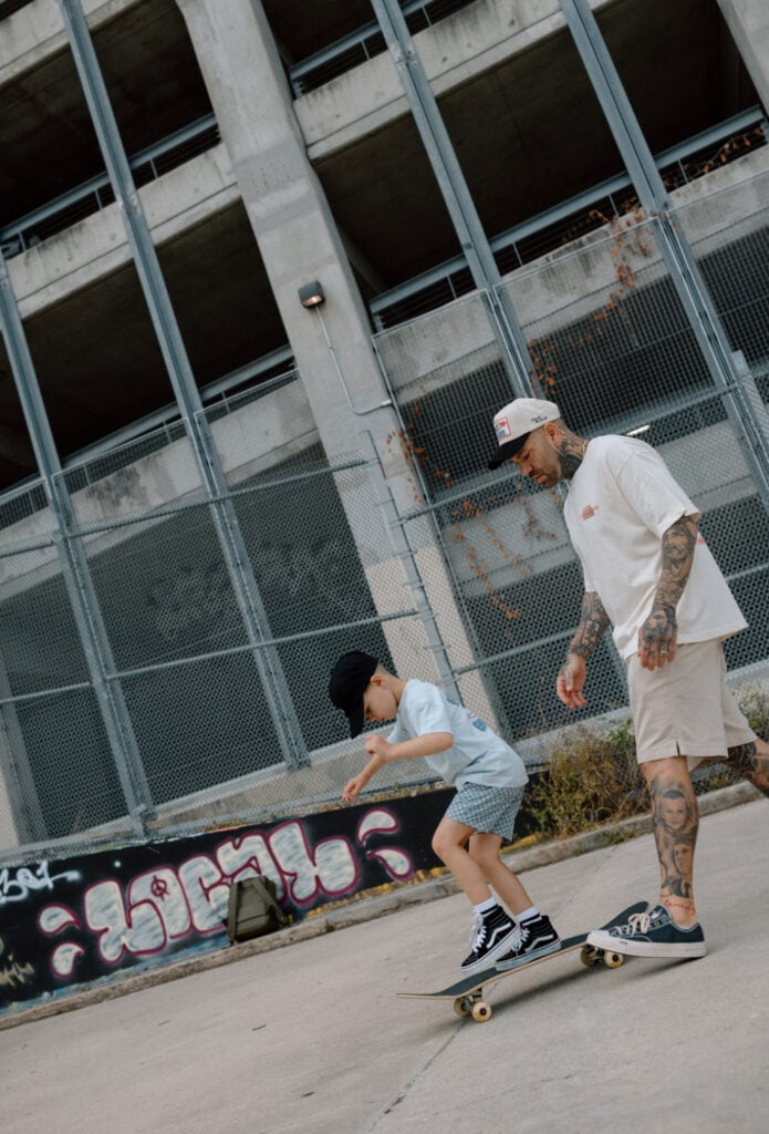 Father watches his young son skateboard during a relaxed Austin lifestyle family photography session.