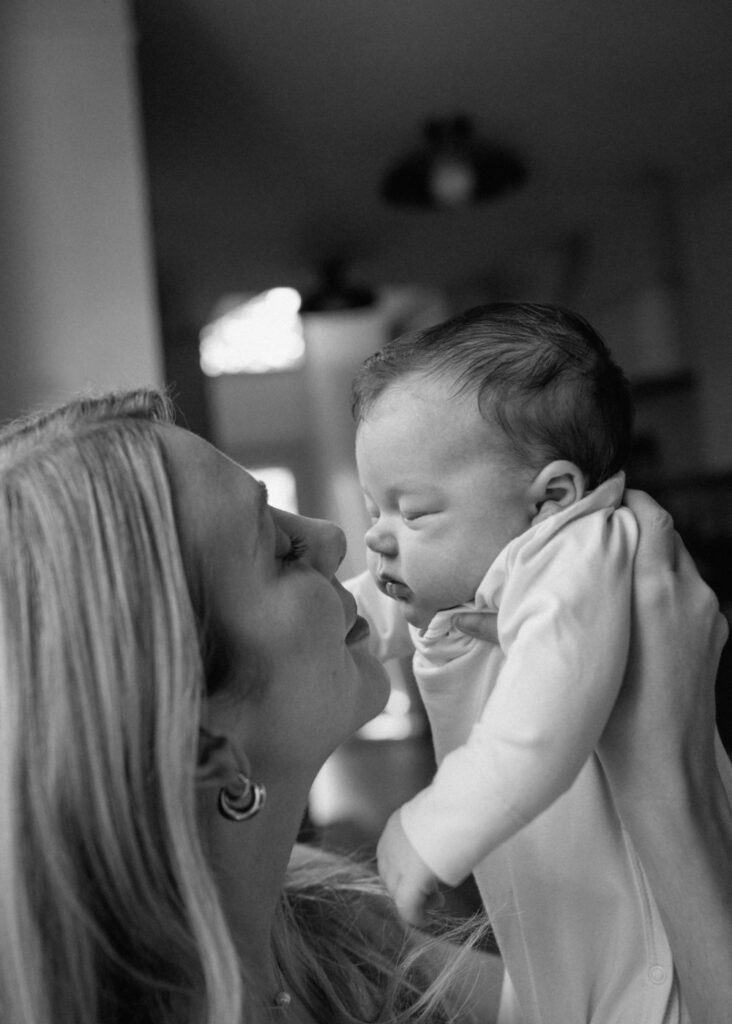 Mom lifts her baby for a sweet kiss in black and white Austin newborn photography.